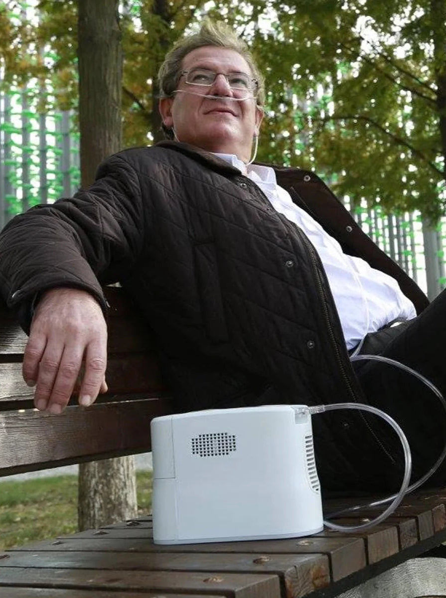 Man sitting on park bench with the Rhythm P2-E6 portable oxygen concentrator sitting next to him enjoying the extended battery life of the portable oxygen concentrator